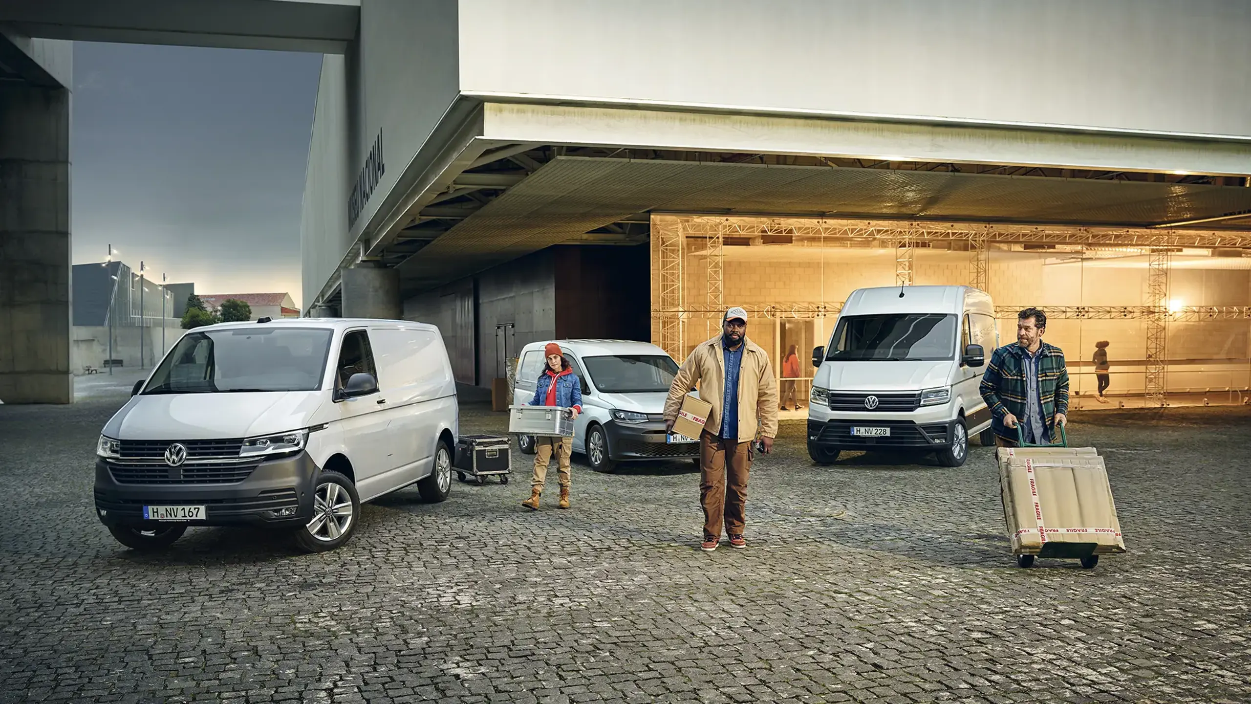 Tre håndværkere går foran tre forskellige parkerede erhvervsbiler i bymiljø