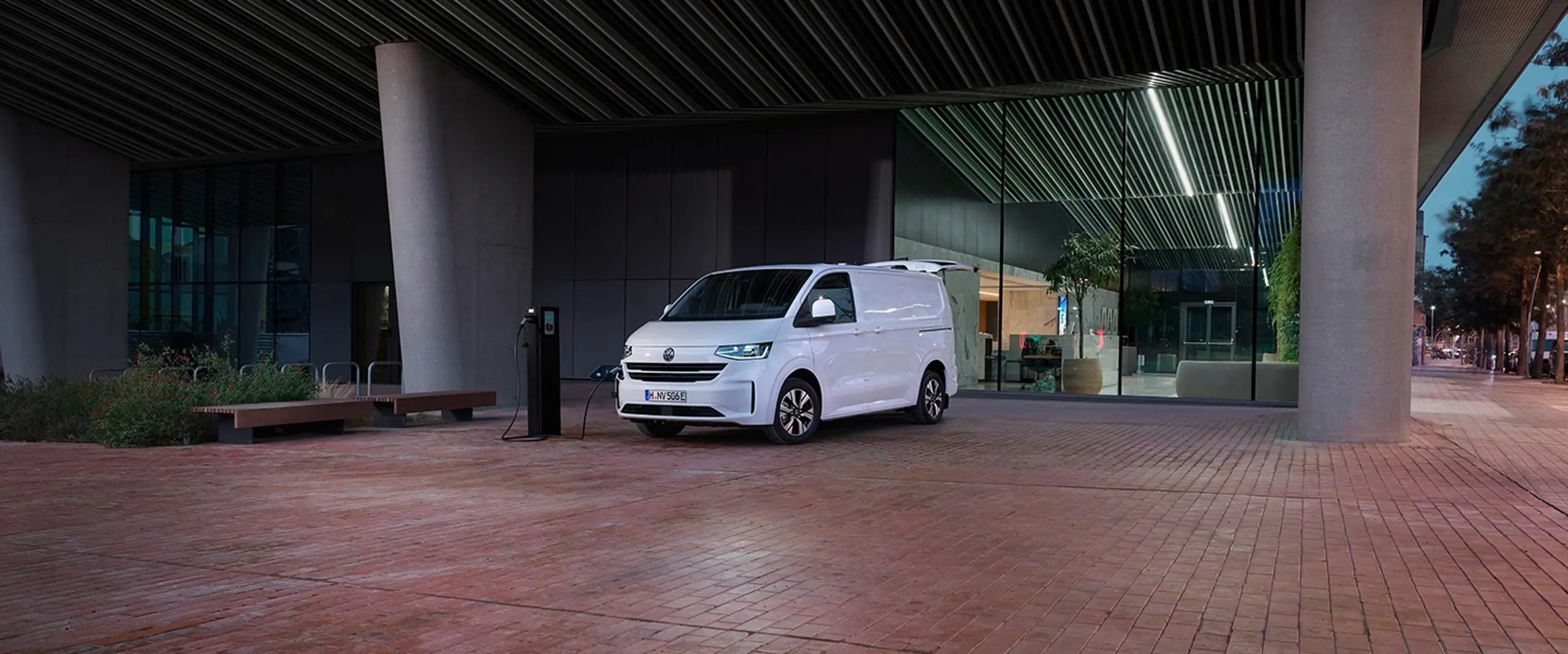 En hvid e-transporter lader foran en bygning