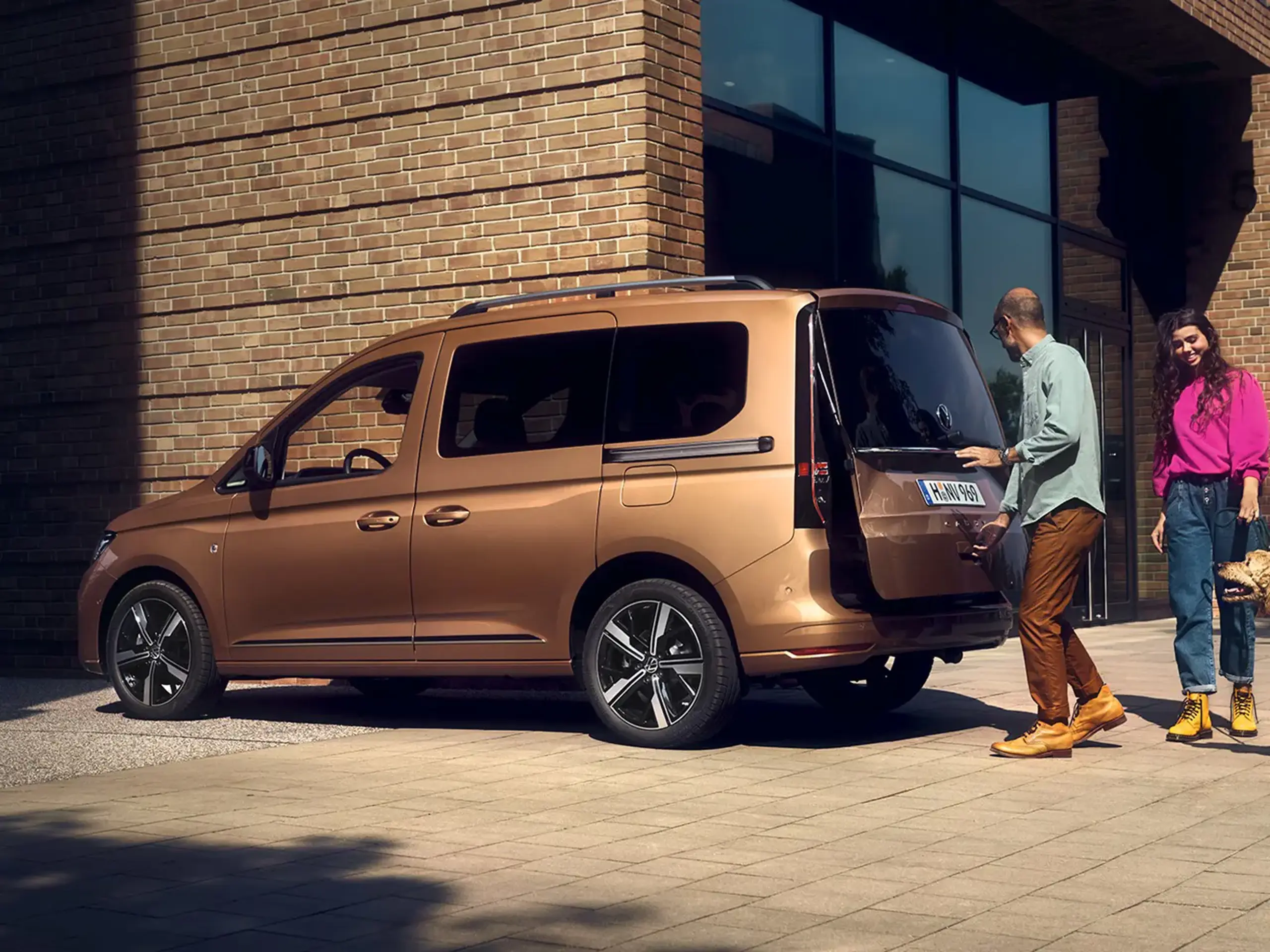 En kvinde og mand er ved at åbne bagagerummet på en Caddy