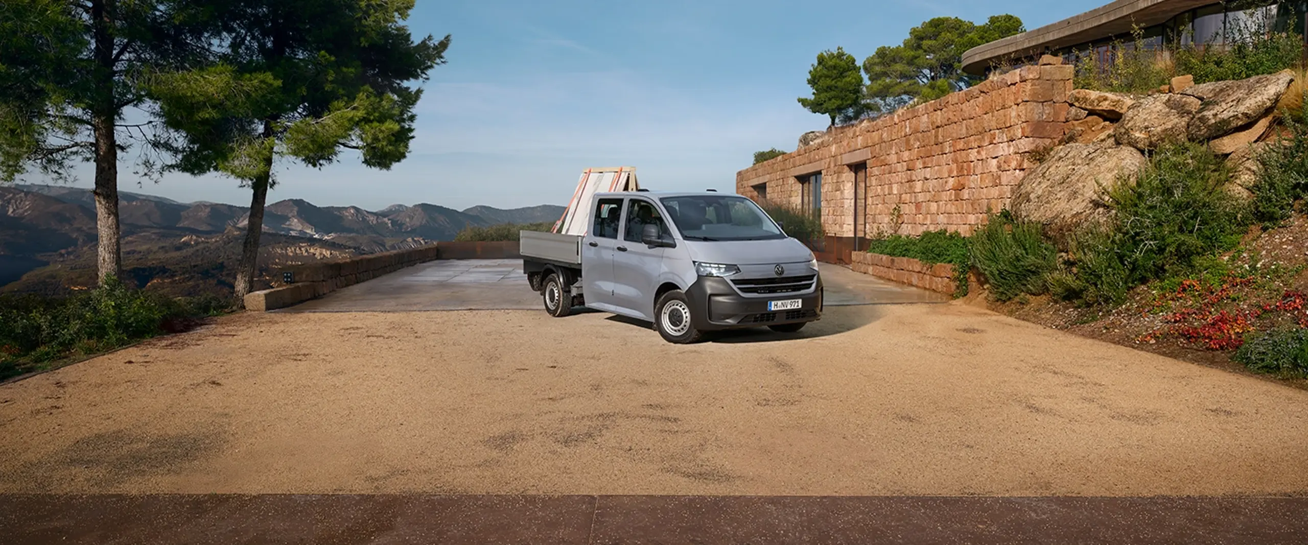 En grå e-transporter på grusparkering i grønne omgivelser