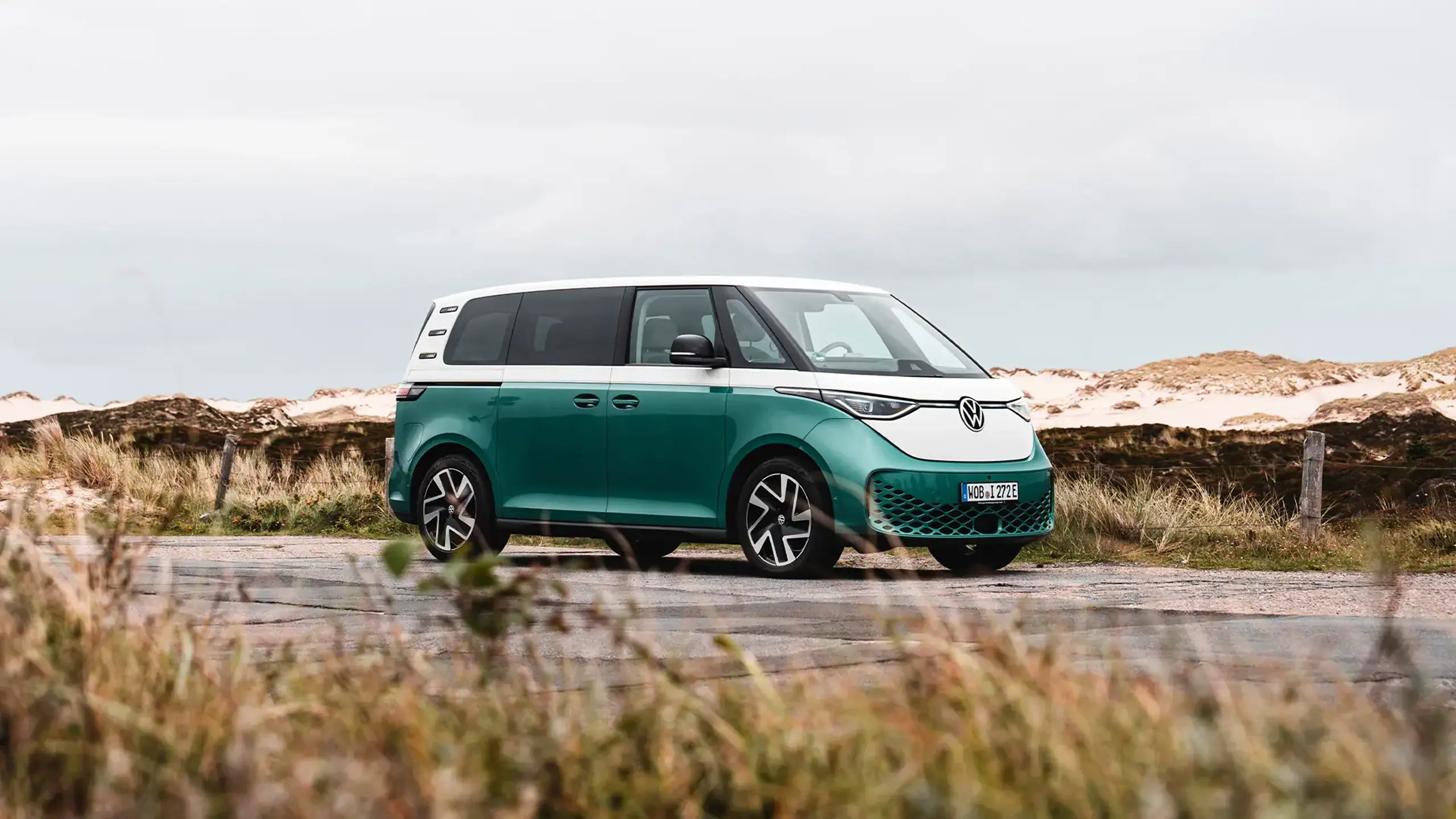 En grøn og hvid ID.Buzz holder parkeret ved en strand