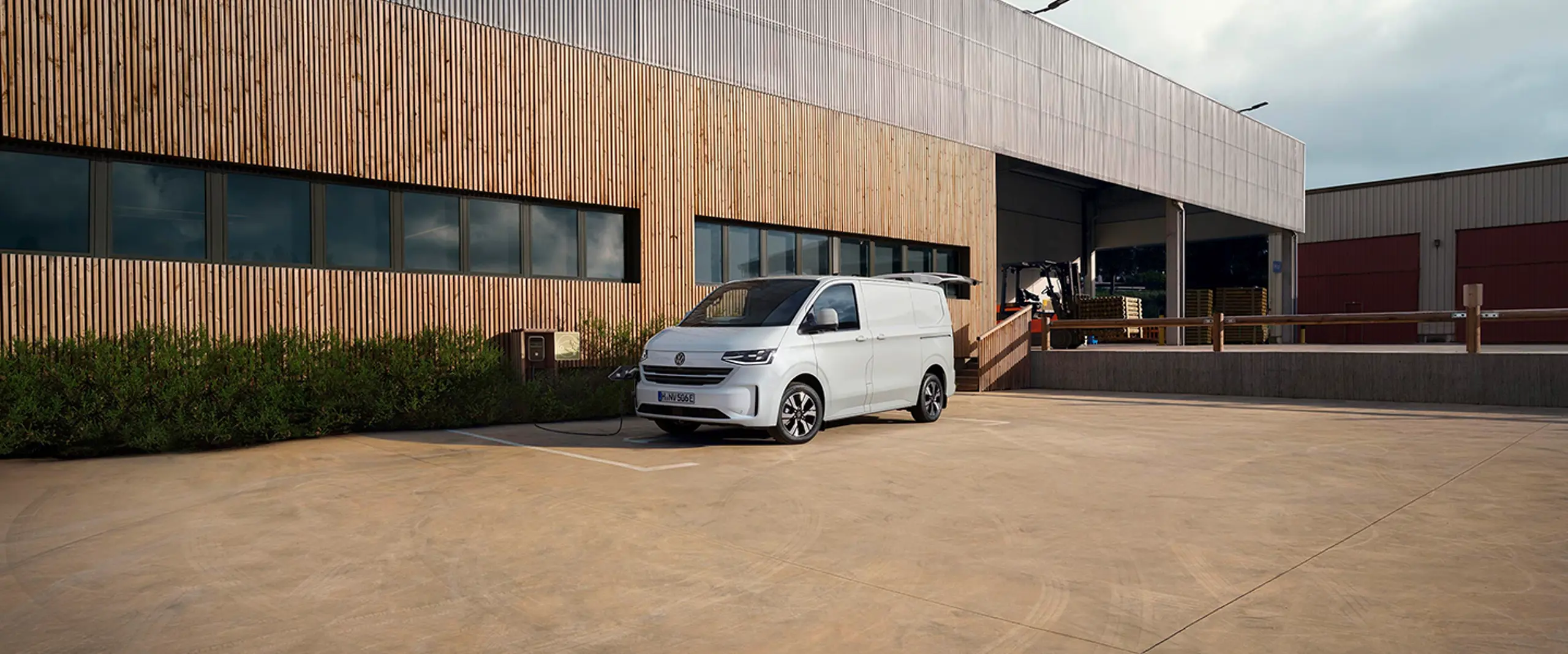 En grå e-transporter foran en bygning med træbeklædning