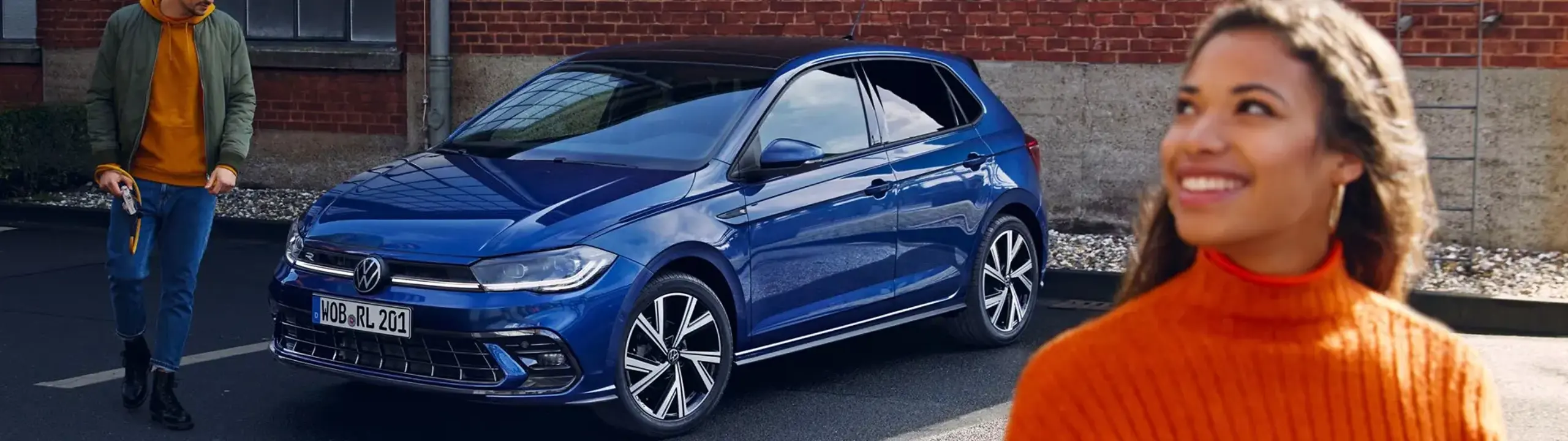 En mand og kvinde går ved en parkeret blå Polo