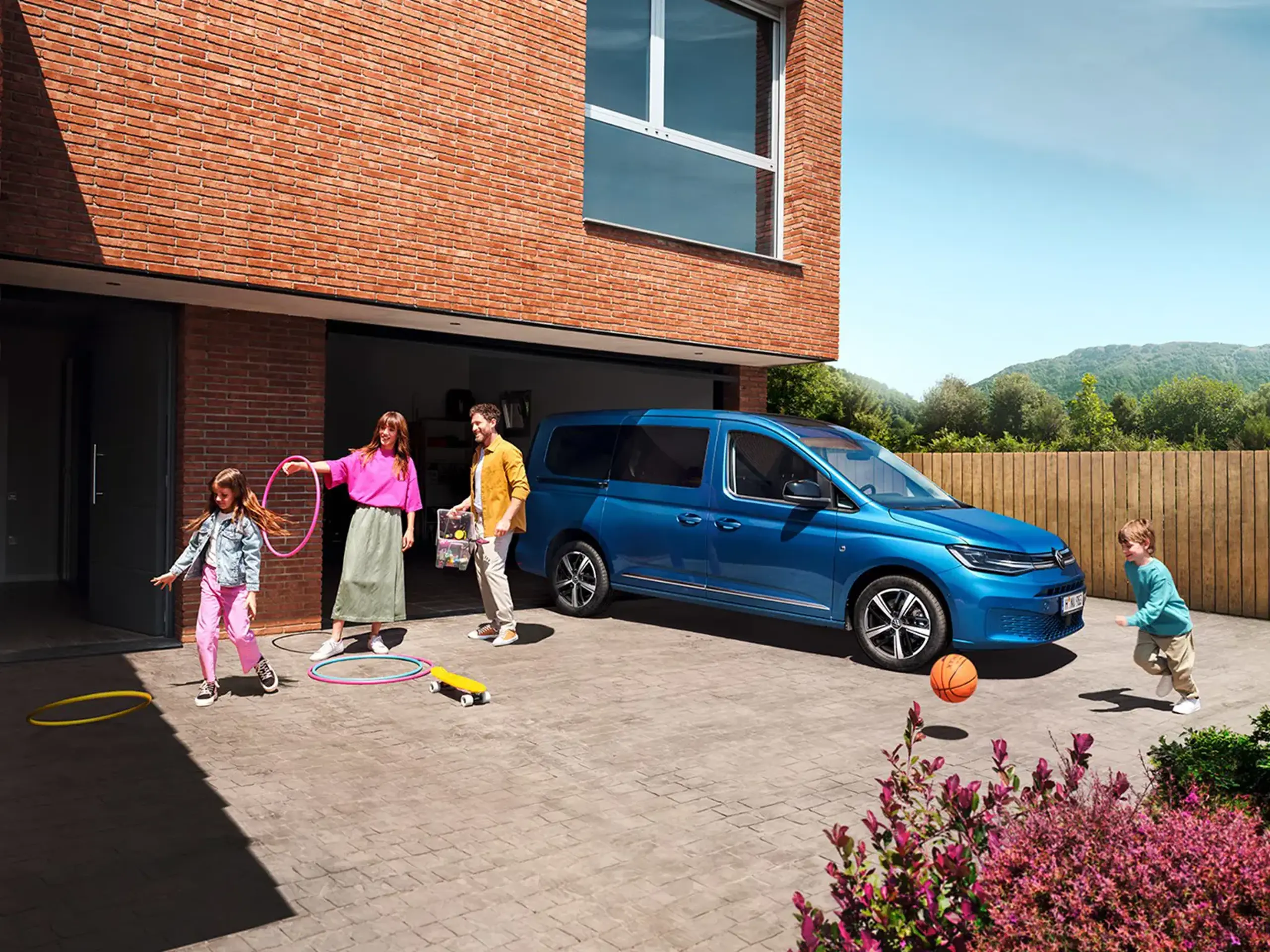 En familie leger omkring en parkeret blå Caddy