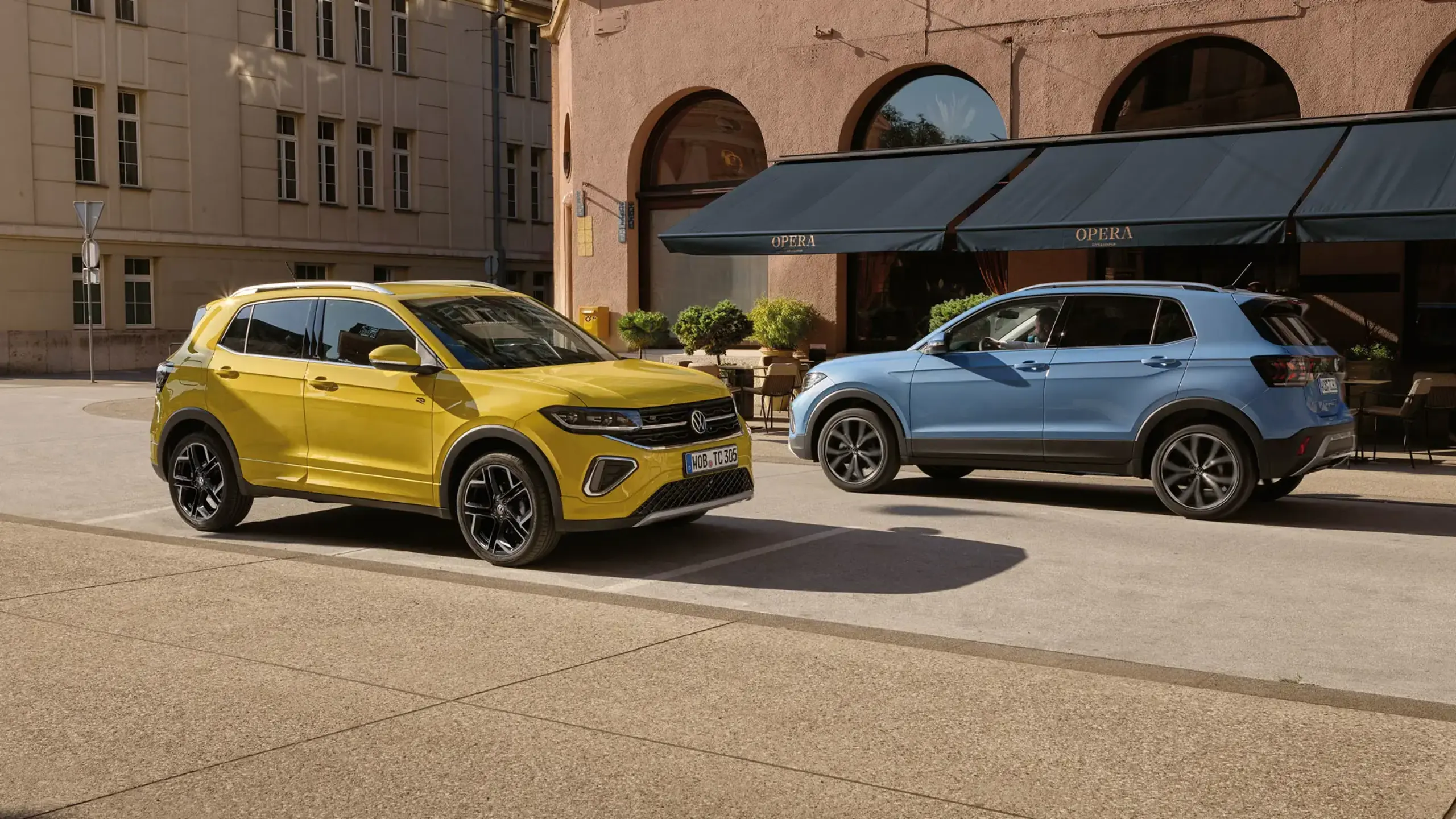 En blå og en gul T-Cross kører forbi hinanden i en by