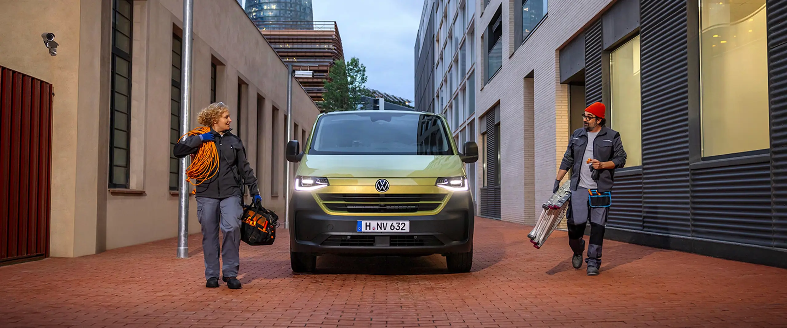 Tå håndværkere ved en grøn e-transporter i by